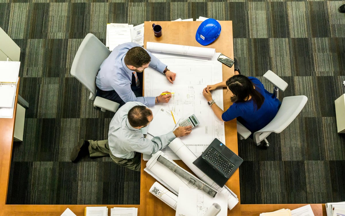 Business people looking over blue prints at a table